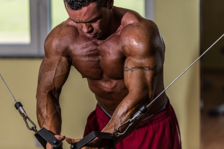shirtless body builder doing standing press white cable for chestの写真素材