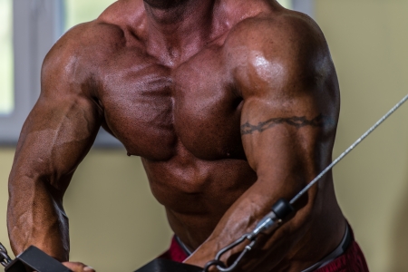 shirtless body builder doing standing press white cable for chestの写真素材