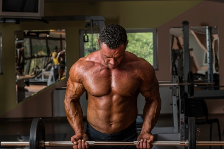 bodybuilder doing heavy weight exercise for biceps with barbellの写真素材