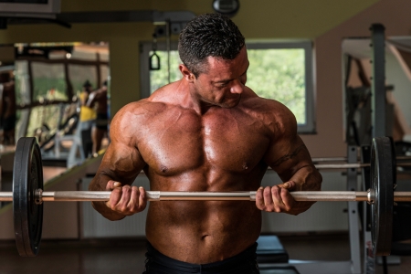 bodybuilder doing heavy weight exercise for biceps with barbellの写真素材