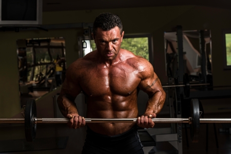 bodybuilder doing heavy weight exercise for biceps with barbellの写真素材