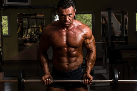 bodybuilder doing heavy weight exercise for biceps with barbellの写真素材