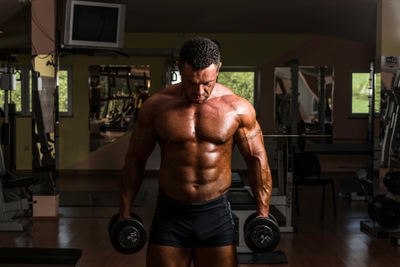 bodybuilder doing heavy weight exercise for biceps with dumbbellの写真素材