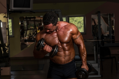bodybuilder doing heavy weight exercise for biceps with dumbbellの写真素材