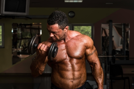 bodybuilder doing heavy weight exercise for biceps with dumbbellの写真素材