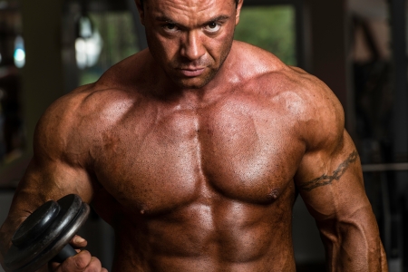 bodybuilder doing heavy weight exercise for biceps with dumbbellの写真素材