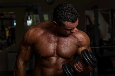 bodybuilder doing heavy weight exercise for biceps with dumbbellの写真素材