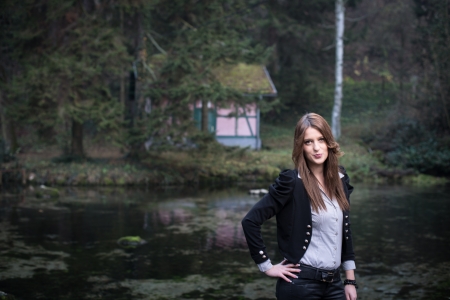 young woman in jacket standing and posing at the lakeの写真素材