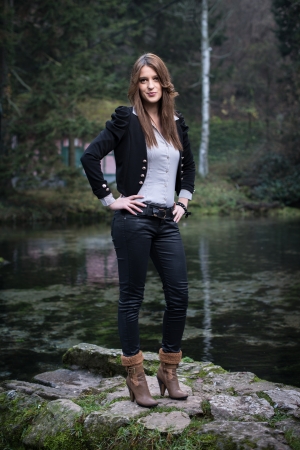 young woman in jacket standing and posing at the lakeの写真素材