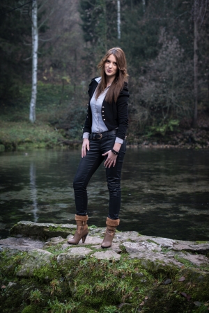young woman in jacket standing and posing at the lakeの写真素材