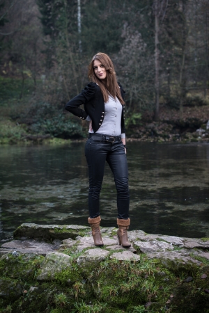 young woman in jacket standing and posing at the lakeの写真素材