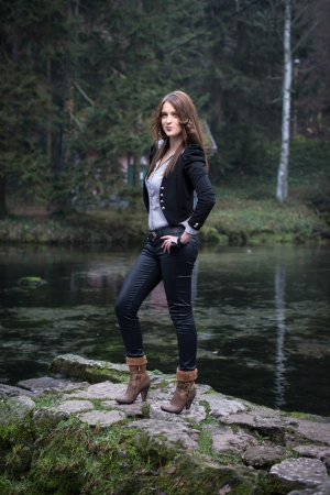 young woman in jacket standing and posing at the lakeの写真素材