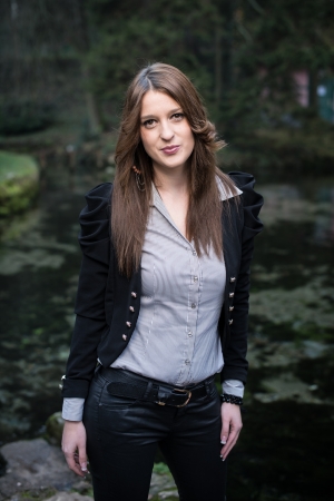 young woman in jacket standing and posing at the lakeの写真素材