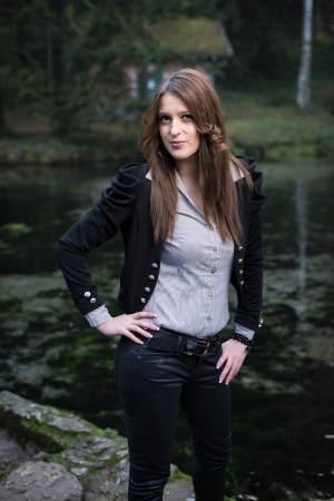 young woman in jacket standing and posing at the lakeの写真素材