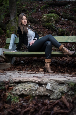 young woman in jacket sitting at the benchの写真素材