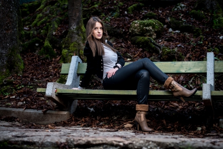 young woman in jacket sitting at the benchの写真素材