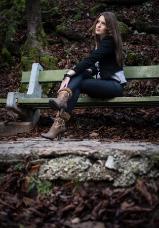 young woman in jacket sitting at the benchの写真素材