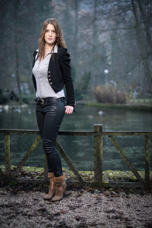 young woman in jacket standing and posing at the lakeの写真素材
