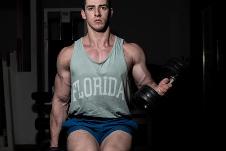young bodybuilder doing heavy weight exercise for biceps with dumbbellの写真素材