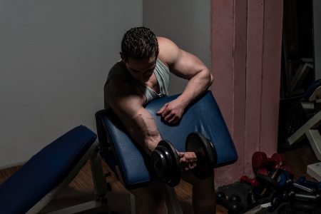 young bodybuilder doing heavy weight exercise for biceps with dumbbellの写真素材
