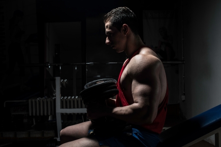 young bodybuilder resting at the bench on black backgroundの写真素材