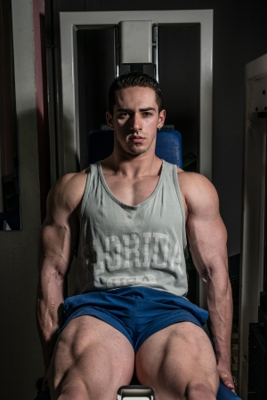 bodybuilder doing heavy weight exercise for legs on machine leg extensionsの写真素材