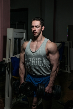 bodybuilder doing heavy weight exercise for shoulder white dumbbellの写真素材