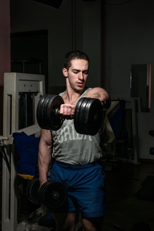 bodybuilder doing heavy weight exercise for shoulder white dumbbellの写真素材