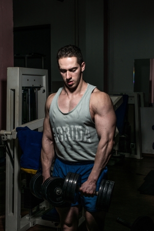 bodybuilder doing heavy weight exercise for shoulder white dumbbellの写真素材