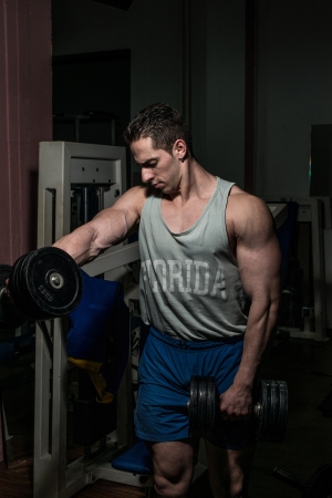 bodybuilder doing heavy weight exercise for shoulder white dumbbellの写真素材