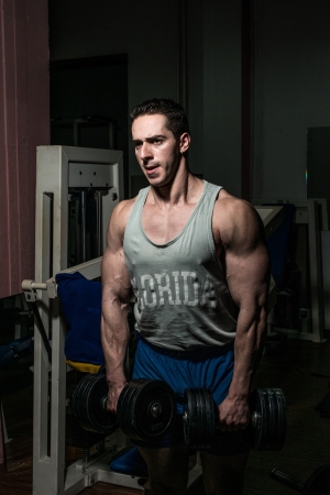 bodybuilder doing heavy weight exercise for shoulder white dumbbellの写真素材