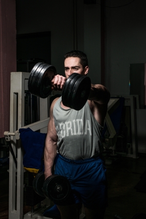 bodybuilder doing heavy weight exercise for shoulder white dumbbellの写真素材