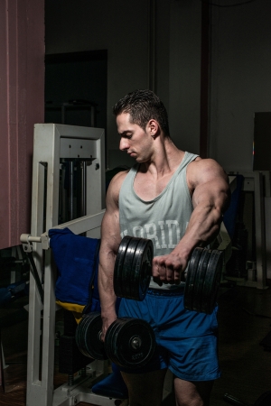 bodybuilder doing heavy weight exercise for shoulder white dumbbellの写真素材