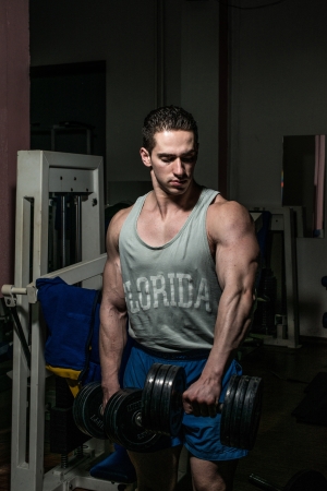bodybuilder doing heavy weight exercise for shoulder white dumbbellの写真素材