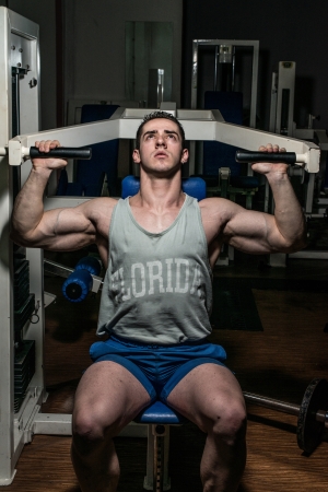 young bodybuilder doing shoulder press on machineの写真素材