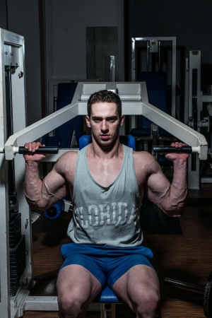young bodybuilder doing shoulder press on machineの写真素材