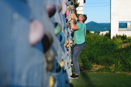 young man climbing wall rock outdoorsの写真素材
