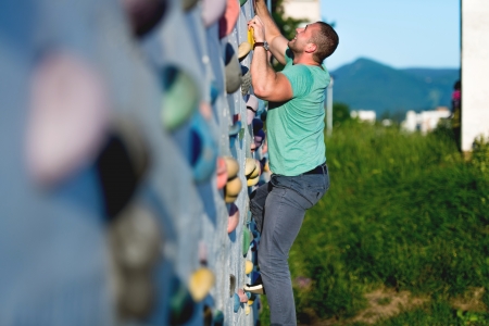 young man climbing wall rock outdoorsの写真素材