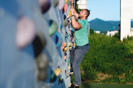 young man climbing wall rock outdoorsの写真素材