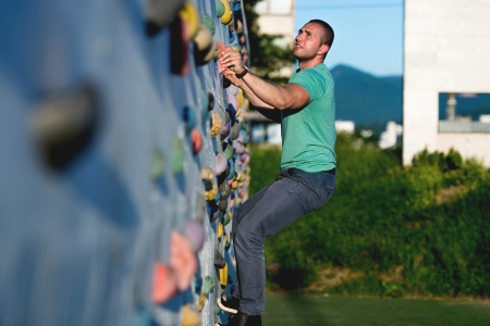 young man climbing wall rock outdoorsの写真素材