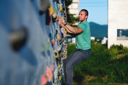 young man climbing wall rock outdoorsの写真素材