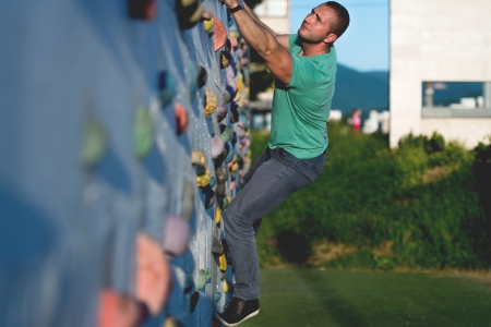 young man climbing wall rock outdoorsの写真素材