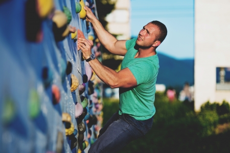 young man climbing wall rock outdoorsの写真素材