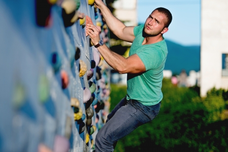 young man climbing wall rock outdoorsの写真素材