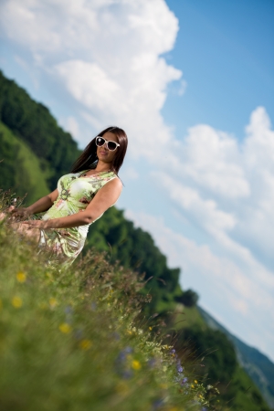 young woman in dress sitting on the grassの写真素材