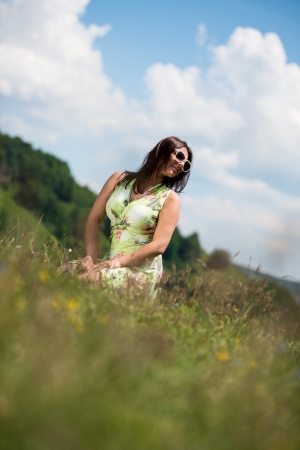 young woman in dress sitting on the grassの写真素材