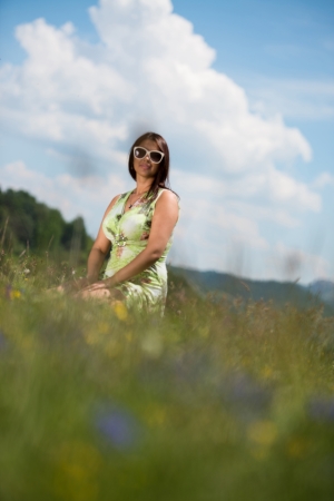 young woman in dress sitting on the grassの写真素材