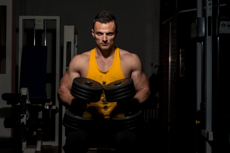 fitness trainer posing with dumbbellsの写真素材