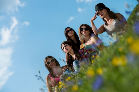 group of girls sitting on grass and having funの写真素材