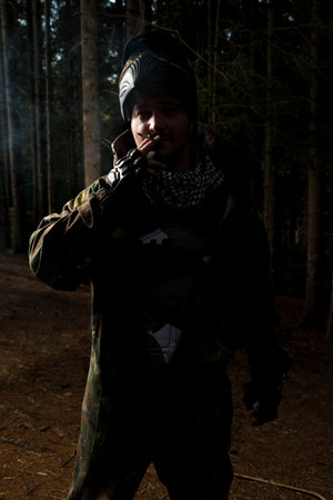 Paintball player smoking a cigarette in the woods